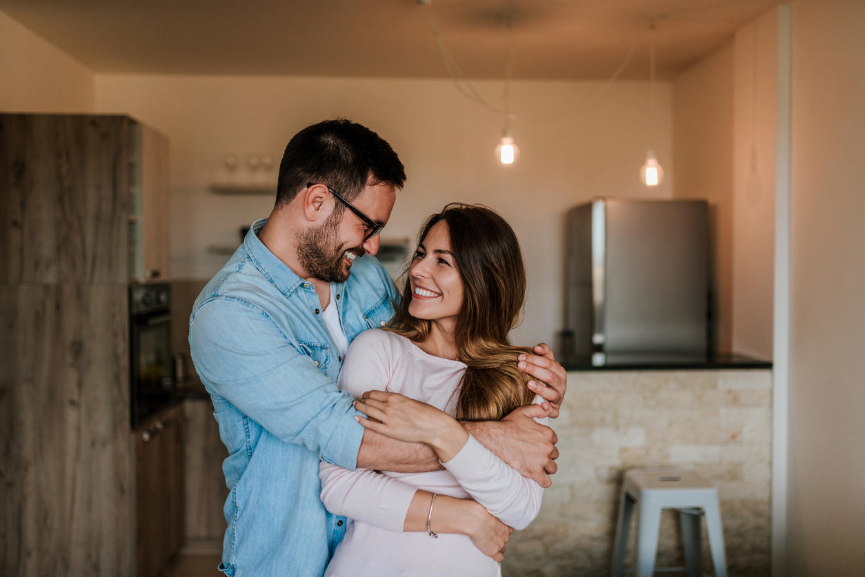 Happy couple in their new home. Young couple hugging indoors.